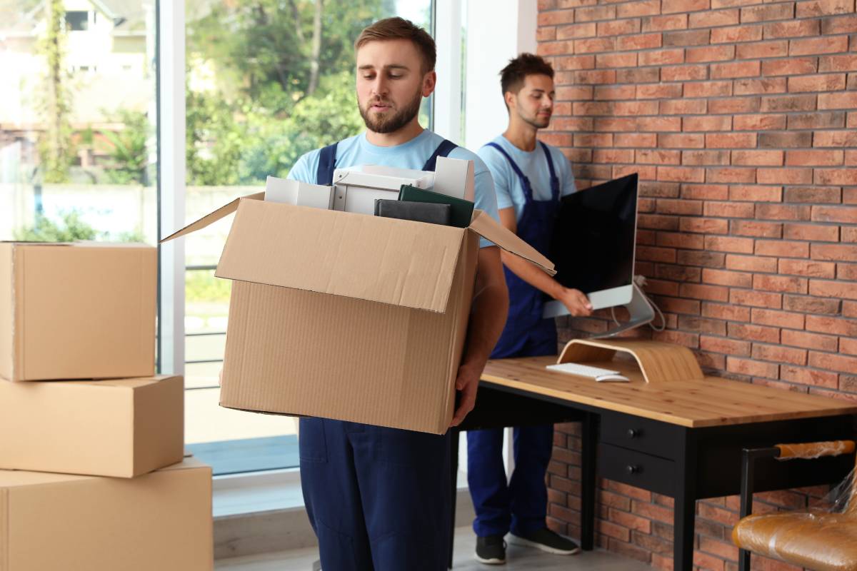 Professionelle Arbeiter, die Sachen aus dem Büro tragen. Umzugsservice