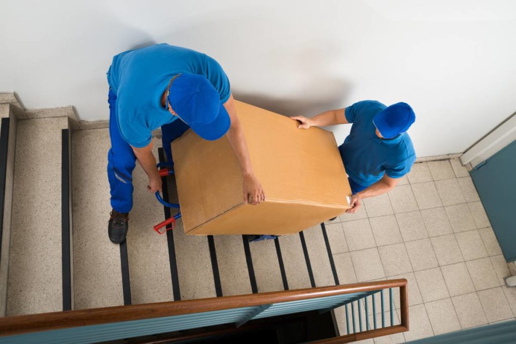 Privatumzüge - Zwei männliche Mover, die mit Kasten auf Treppe nach unten gehen